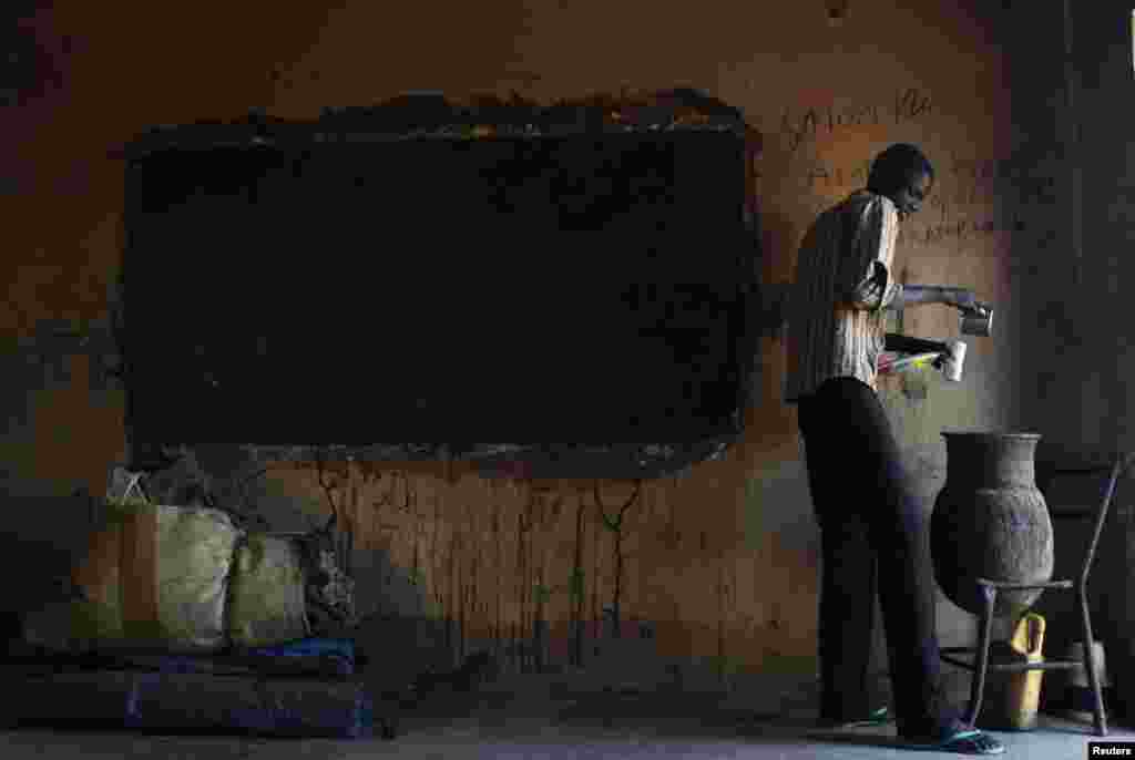 A man pours drinking water at a former school near polling station in Abyei, Oct. 28, 2013.