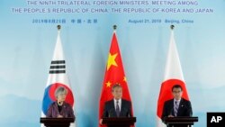 资料照片:2019年8月21日,中国外长王毅(中)、韩国前外长康京和(左)、日本前外相河野太郎在北京举行三国外长会谈后出席联合记者招待会。(美联社)