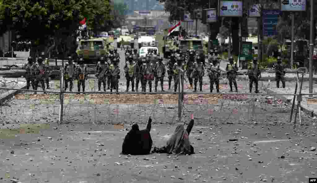 Para pendukung Presiden Mesir yang terguling Mohamed Morsi duduk di depan pagar kawat berduri yang menghalangi akses ke markas Garda Republik di Kairo.