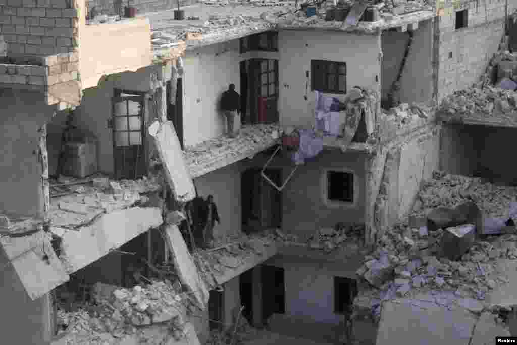 Warga memeriksa rumah-rumah merekamenyusul serangan udara yang menurut para aktivis dilakukan oleh pasukan pendukung setia Presiden Suriah Bashar Al-Assad di Al-Maysar, Aleppo (19/1).