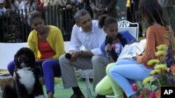 El presidente Barack Obama, Michelle Obama, y la mascota familiar, Bo, escuchan a las hijas de la pareja presidencial Sasha y Malia.