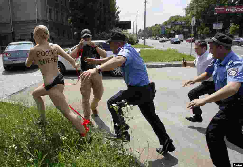 Pejabat Kementerian Dalam Negeri Ukraina dan penjaga keamanan mengejar seorang aktivis dari kelompok hak-hak perempuan FEMEN, ketika melakukan demonstrasi di Kedutaan Besar Rusia menanggapi pengumuman Presiden Rusia Vladimir Putin yang menyatakan perceraian dengan istrinya Lyudmila, di Kiev. Kata-kata yang tertulis di punggung perempuan itu berbunyi "Dorong Rusia untuk Maju"