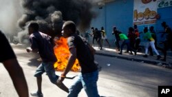 Los manifestantes pasan por una barricada cercana a un depósito que estaba siendo saqueado, durante una protesta, en Haití.