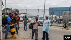 Seorang perawat dari Kementerian Kesehatan Nasional mengawal seorang pelawat ke bagian tes COVID-19 sebelum memasuki wilayah Afrika Selatan di pos perbatasa Beitbridge antara Afrika Selatan dan Zimbabwe dekat South Africa and Zimbabwe, near Musina, South Africa, Jan. 8, 2021. 