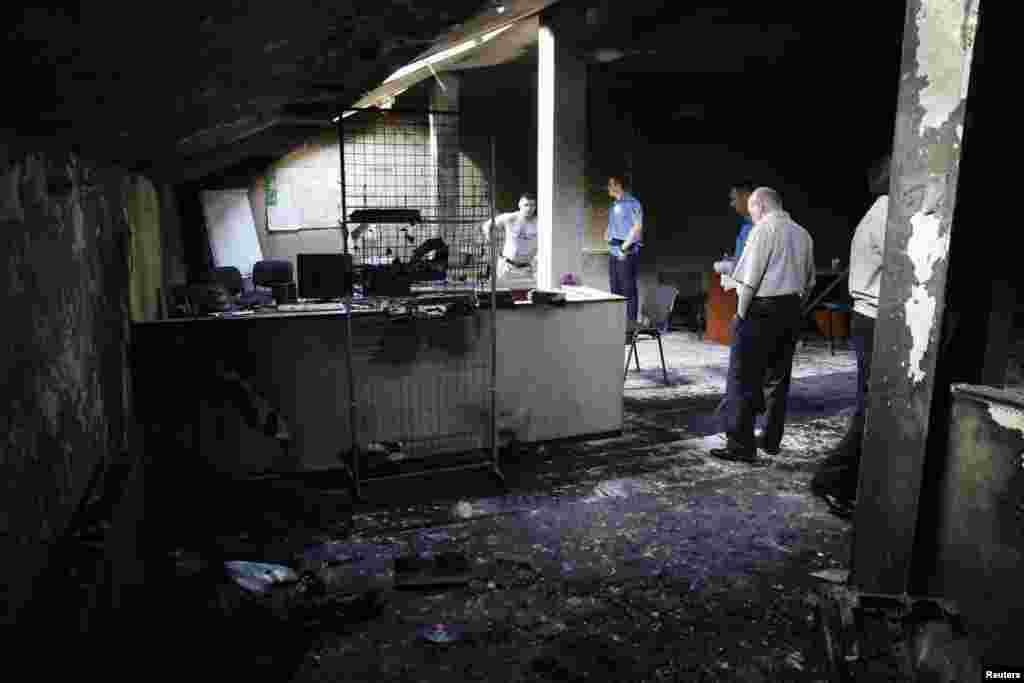 Interior Ministry security force members and investigators work inside a burned out regional office of the All-Ukrainian Union "Svoboda" (Freedom) Party, led by Oleh Tyahnybok, in Odessa, May 28, 2014.