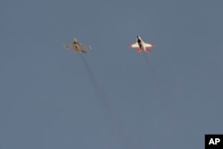 An AI-enabled U.S. Air Force F-16 fighter jet, the X-62A VISTA, right, flies nose to nose with an adversary F-16, as both aircraft raced within 1,000 feet of each other, May 2, 2024, above Edwards Air Force Base, Calif. (AP Photo/Damian Dovarganes)