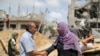 Un hombre y una mujer palestinos se saludan entre escombros en la Franja de Gaza el 21 de mayo de 2021, después de la tregua acordada entre Israel y Gaza.