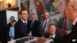 ប្រធានាធិបតី​បារាំង Emmanuel Macron (ឆ្វេង) ចាប់​រលាក់​ដៃ​ជា​មួយ​មន្ត្រី​នៅ​ការិយាល័យ​បោះ​ឆ្នោត​ ក្នុង​ពេល​បោះ​ឆ្នោត​​សភា​ជុំ​ទី២ នៅក្រុង Le Touquet ភាគ​ខាង​កើត​នៃ​ប្រទេស​បារាំង កាល​ពី​ថ្ងៃទី​១៨ ខែ​មិថុនា។