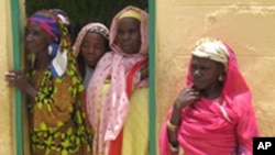 Women peer out of a doorway at the Kwali rehabilitation center for fistula in Kano, northern Nigeria, August 17, 2005.