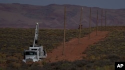 A crew with the Navajo Tribal Utility Authority installs power poles, Oct. 9, 2024, on the Navajo Nation in Halchita, Utah.
