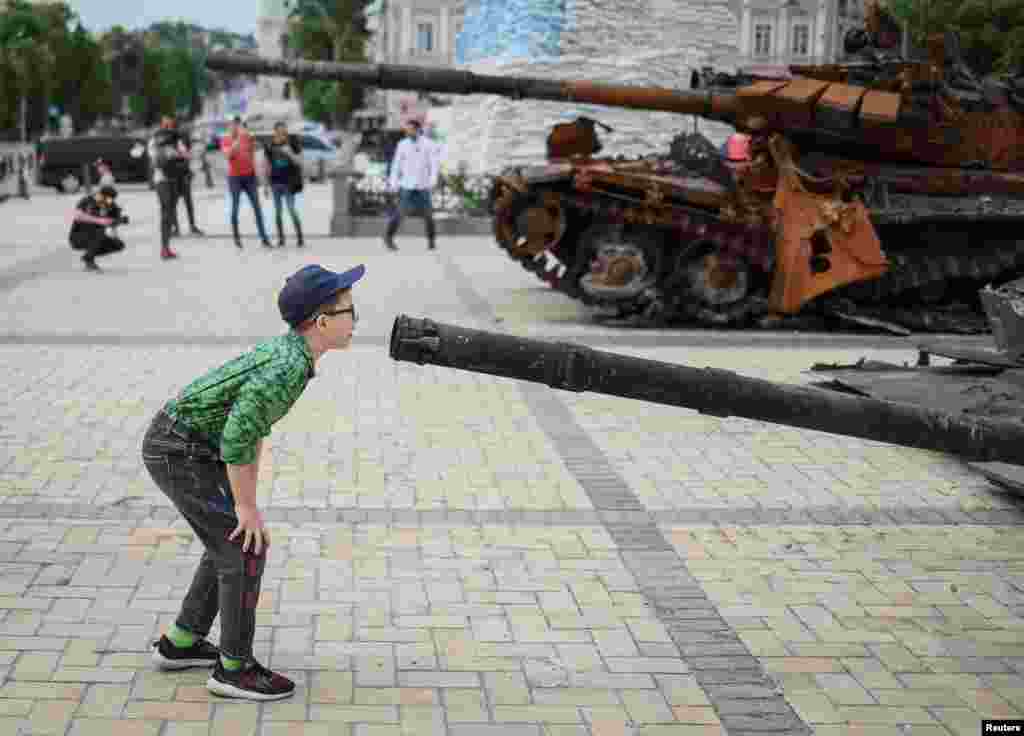 Un niño observa un tanque de guerra ruso destruido en una exposición de vehículos militares rusos en el centro de Kiev, Ucrania, el 21 de mayo de 2002. 