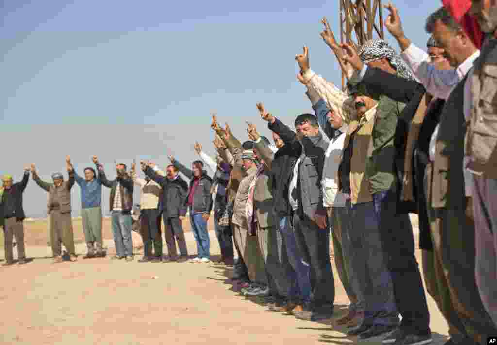 Des Kurdes font le signe de victoire lors d'un rassemblement de solidarité avec la ville syrienne de Kobané dans le village de Caykara, Turquie, le 11 novembre 2014.