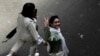 FILE - An Iranian woman without a mandatory headscarf, or hijab, flashes a victory sign as she walks at the old main bazaar of Tehran, Iran, June 13, 2024. 