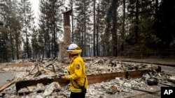 Cal Fire Division Chief Carmel Barnhart inspects a property, Aug. 18, 2021, after the Caldor Fire burned through Grizzly Flats, Calif. 