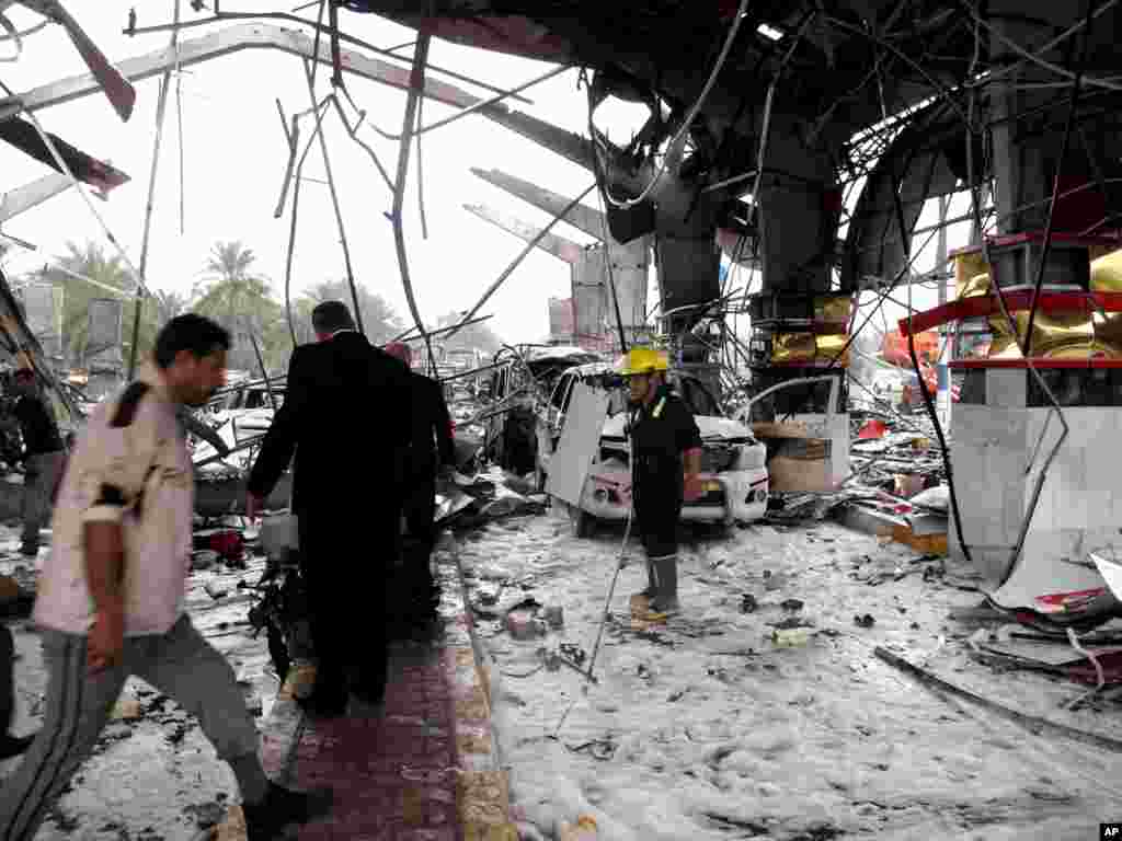 Security forces and civilians inspect the site of a massive bomb attack where a suicide car bomber set off his explosive-laden vehicle at a security checkpoint, Hillah, Iraq, March 9, 2014.
