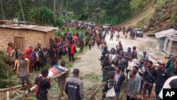 En esta fotografía proporcionada por la Organización Internacional para las Migraciones, una persona lesionada es cargada en una camilla para solicitar asistencia médica tras un deslave en el poblado de Yambali, el viernes 24 de mayo de 2024, en Papúa Nueva Guinea.