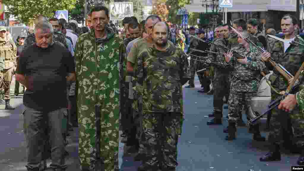 Armed pro-Russian separatists, right, escort a column of Ukrainian prisoners of war as they walk across central Donetsk, Ukraine, Aug. 24, 2014.