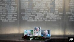 Flowers are placed by portraits of slain journalists Alexander Rastorguyev, Kirill Radchenko and Orkhan Dzhemal, at the Russian journalists Union building in Moscow, Russia, Wednesday, Aug. 1, 2018. 