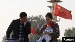 一对中国年轻夫妇在北京天安门用手机给他们的婴儿拍照 （资料照片）
