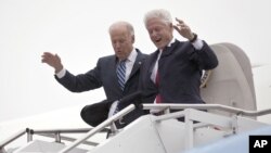 El vicepresidente Joe Biden acompaña al presidente Bill Clinton, mientras descienden cuidadosamente del avión durante una tormenta en Youngstown, Ohio. Tanto Romney como Obama suspendieron su agenda personal de campaña por la arremetida de 'Sandy'.