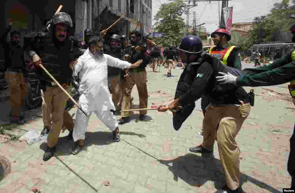 Police beat a supporter of Tahir-ul Qadri of the political party Pakistan Awami Tehreek during a protest in Lahore, Pakistan, June 17, 2014.