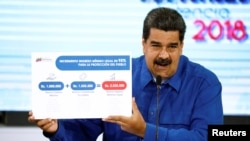 Venezuela's President Nicolas Maduro holds a poster explaining the new minimum wage as he speaks during a news conference in Caracas, April 30, 2018. 