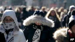 Pedestrians try to keep warm while walking in New York's Times Square, Dec. 27, 2017. Freezing temperatures and below-zero wind chills socked much of the northern United States, and the snow-hardened city of Erie, Pa., dug out from a record snowfall.