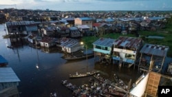 Los espectadores se sientan en botes viendo una película proyectada en una pantalla instalada sobre una estructura de madera durante el Festival de Cine Flotante Muyuna, que celebra los bosques tropicales, en el barrio Belén de Iquitos, Perú, el 25 de mayo de 2024.