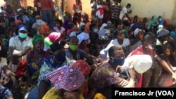 Deslocados, vítimas, da violência armada em Cabo Delgado aguardam na rua com as senhas para adquirir os seus produtos através da ajuda do PMA, em Pemba.