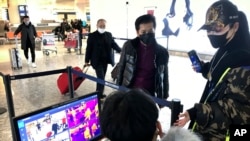 FILE - Travelers pass through a health screening checkpoint at Wuhan Tianhe International Airport, in Wuhan, in southern China's Hubei province, Jan. 21, 2020.