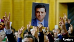 FILE - A supporter holds a portrait of Selahattin Demirtas, detained leader of Turkey's pro-Kurdish opposition Peoples' Democratic Party at a meeting at the Turkish parliament in Ankara.