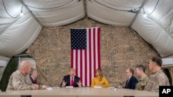 President Trump, accompanied by national security adviser John Bolton, third from left, first lady Melania Trump, fourth from right, U.S. Ambassador to Iraq Doug Silliman, third from right, and senior military leadership, speaks to members of the media at Al Asad Airbase, Iraq.