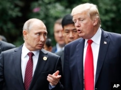 U.S. President Donald Trump and Russia's President Vladimir Putin talk during a photo session at the APEC Summit in Danang, Vietnam, Nov. 11, 2017.