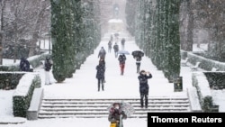 People walk during heavy snowfall in Retiro park in Madrid, January 8, 2021.