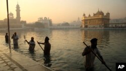 FILE- In this Nov. 17, 2013, file photo, Indian Sikh devotees clean the tank early in the morning at the Golden Temple, on the birth anniversary of Guru Nanak, the first Sikh Guru in Amritsar, India. The chronic air pollution is now threatening the holiest shrine in the Sikh religion, making the once-gleaming walls of the Golden Temple dingy and dull.