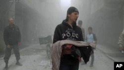 This photo provided by the anti-government activist group Aleppo Media Center (AMC), which has been authenticated based on its contents and other AP reporting, shows a Syrian man carrying the body of a child killed by a government forces airstrike in the 