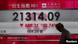 Un hombre camina frente a un panel que muestra valores del índice Hang Seng en la tarde del primer día de actividades de 2016, en Hong Kong, China. Enero 4, 2016.