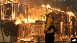 A firefighter monitors a house burning in Santa Rosa, Calif., Oct. 9, 2017. 