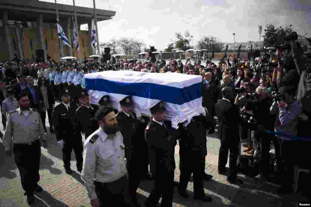 Members of the Knesset guard carry the flag draped coffin of former Prime Minister Ariel Sharon as his family members walk behind during a memorial ceremony at Israel's parliament in Jerusalem, Jan. 13, 2014.