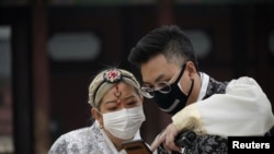 在南韓首爾市中心的景福宮，一對戴著口罩的情侶在看手機。(2020年3月1日)