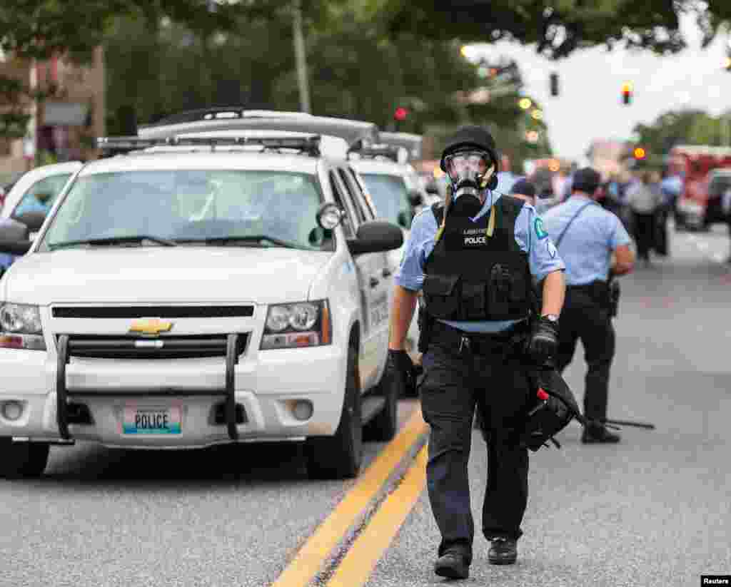 Police wear gas masks as they attempt to disperse a crowd that gathered after a shooting incident in St. Louis, Missouri Aug. 19, 2015. 