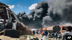 People are seen in front of clouds of black smoke from fires in the aftermath of an airstrike in Mekelle, capital of the Tigray region of northern Ethiopia, Oct. 20, 2021. Ethiopian forces carried out another airstrike on the city Oct. 21. 