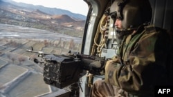 Taliban security personnel keep watch from a helicopter two days after airstrikes by Pakistan in the Barmal district of eastern Paktika province, Afghanistan, on Dec. 26, 2024.