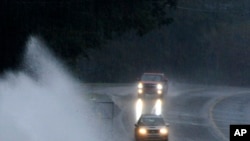 Varios automóviles avanzan por un camino con muchos charcos en Helena, Alabama, el viernes 25 de octubre. AP.