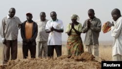 A family gathers around the grave, where three murdered family members were buried together, in Jos in Nigeria's Plateau state, December 28, 2011. Armed Fulani herdsmen shot dead three members of a family in an attack in Nigeria's ethnically and religious