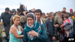 A migrant cries as she tries to break through the cordon of Macedonian police forces, while waiting to board a bus after crossing the Macedonian-Greek border near Gevgelija on Sept. 10, 2015. 