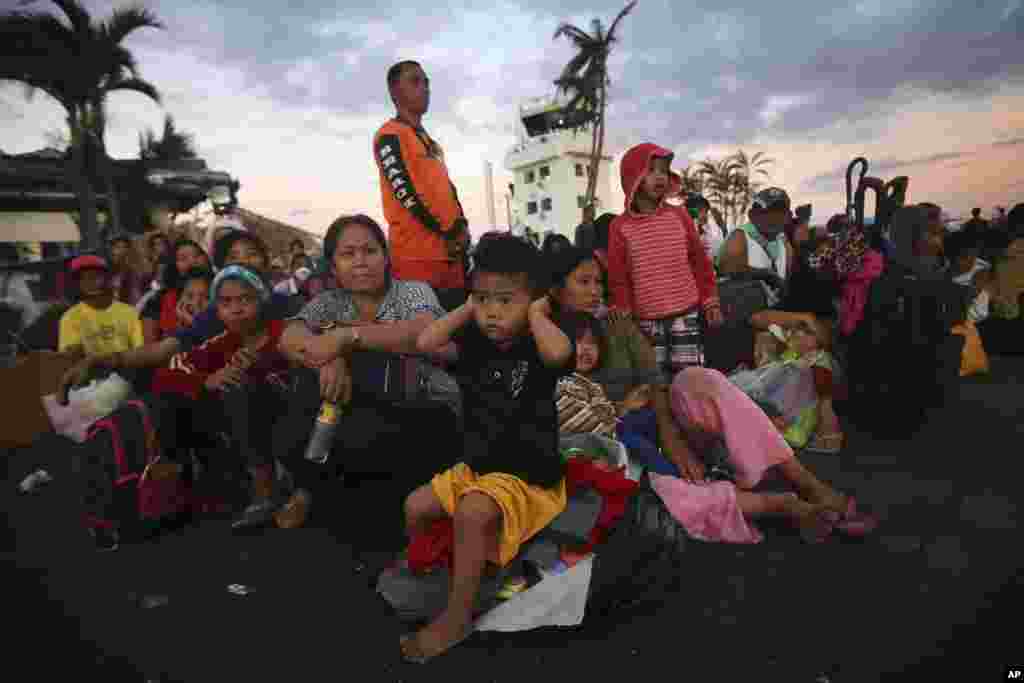 A young boy, a survivor of Typhoon Haiyan covers his ears as military C-130 aircraft land at the airport in Tacloban, central Philippines, Nov. 15, 2013.