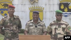 Msemaji wa Kamati ya Mpito na Urejeshaji wa Taasisi (CTRI), Kanali Ulrich Manfoumbi Manfoumbi (kati) akisoma taarifa kwenye televisheni. AFPTV