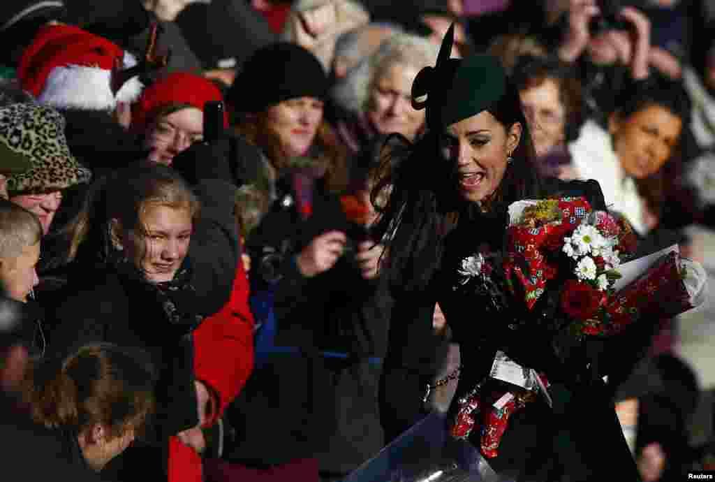 Britain's Catherine, the Duchess of Cambridge, rushes to collect flowers from well-wishers as she leaves a Christmas Day morning service at the church on the Sandringham Estate in Norfolk, eastern England.