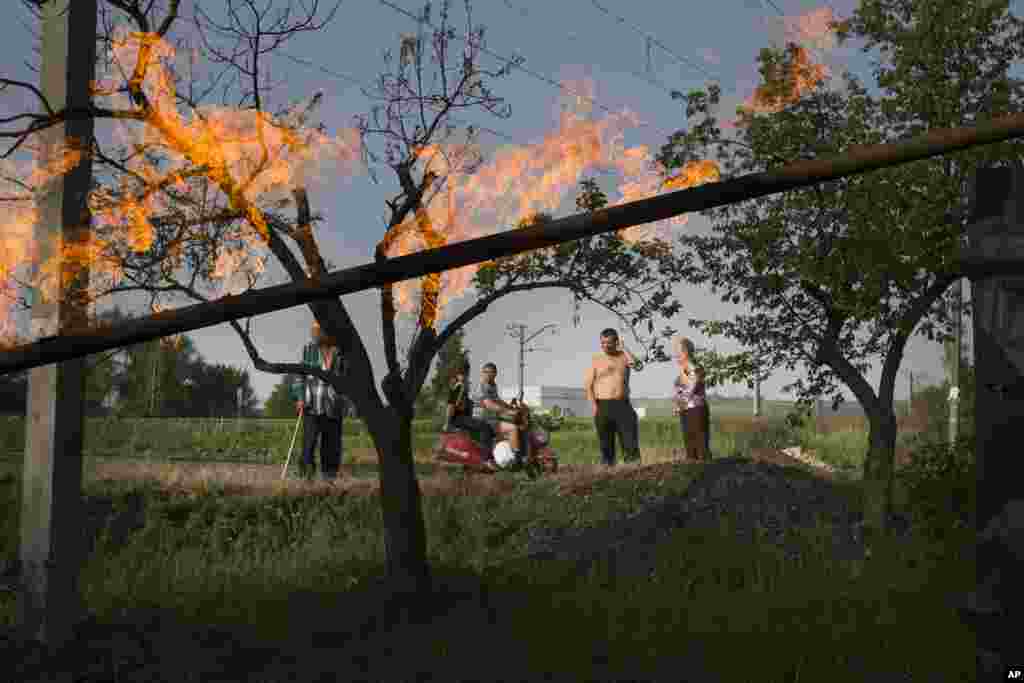 Residents watch the flames from a damaged gas pipe that was hit by a mortar bomb, during fighting between Ukrainian government troops and pro-Russian militants, outside Slovyansk, Ukraine, May 19, 2014. 